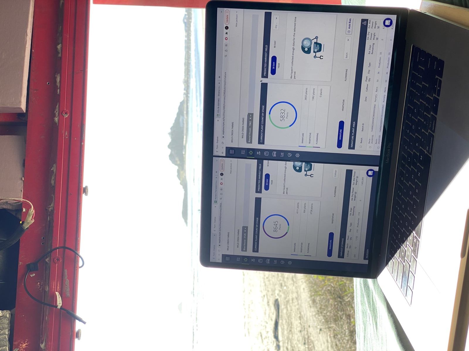 Laptop open in a van at the beach showing Trym cultivation management software — Wildcreek Farms data visible, Trinity County mountains in the background, four hours from the facility.
